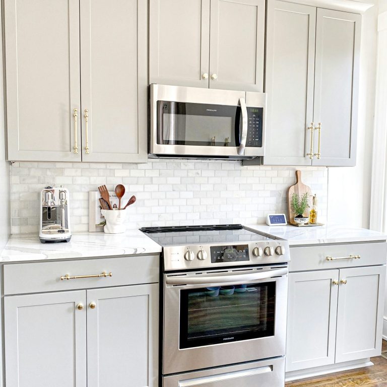 Cocina moderna con muebles grises, estufa de acero inoxidable y electrodomésticos.